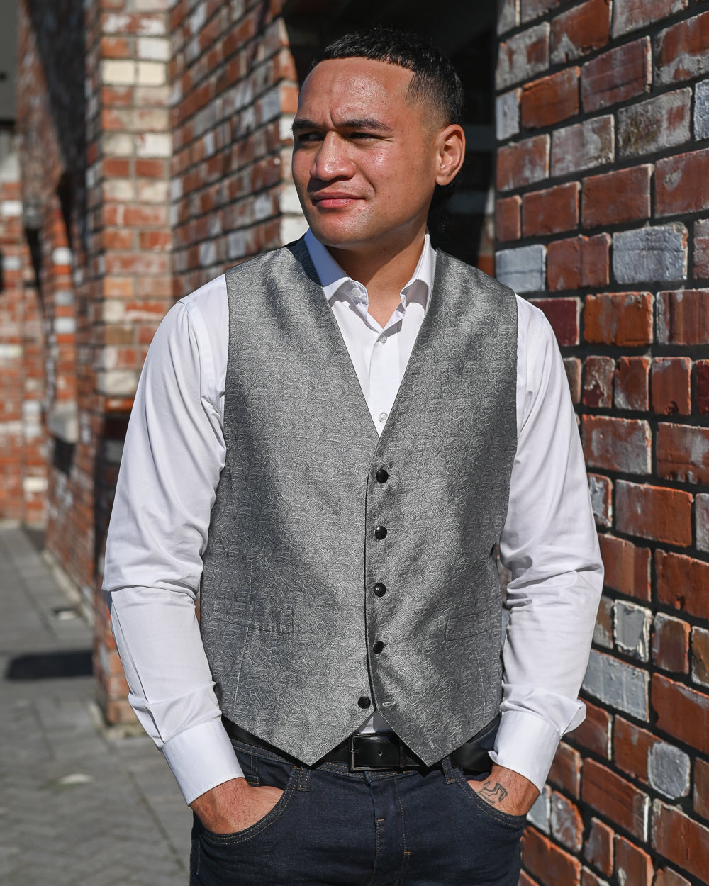 Young man wearing silver grey waistcoat with white shirt and jeans