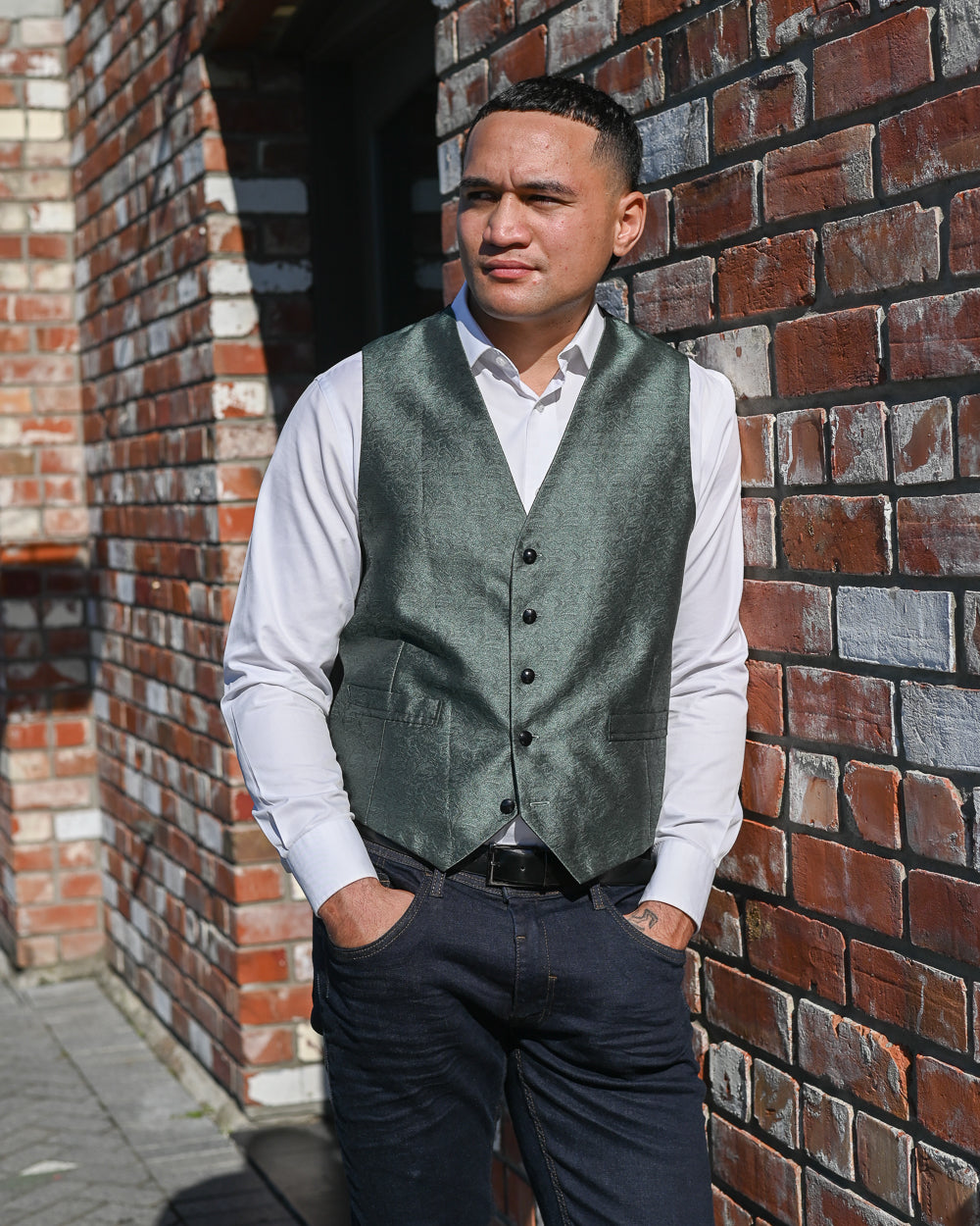Handsome young Samoan man wearing a green waistcoat with a white shirt and jeans