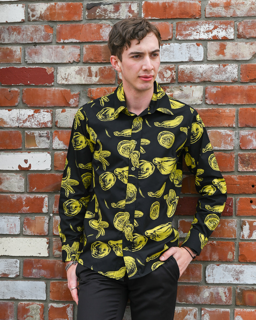Man wearing a long-sleeve cotton, fruit print shirt. Made in collaboration between textile artist Mark Taylor and Mr Peacock
