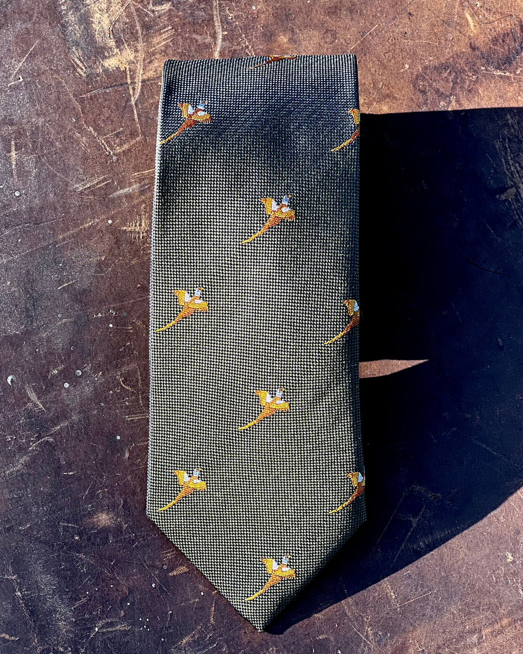 Silk tie featuring a gold pheasant motif against an olive green background