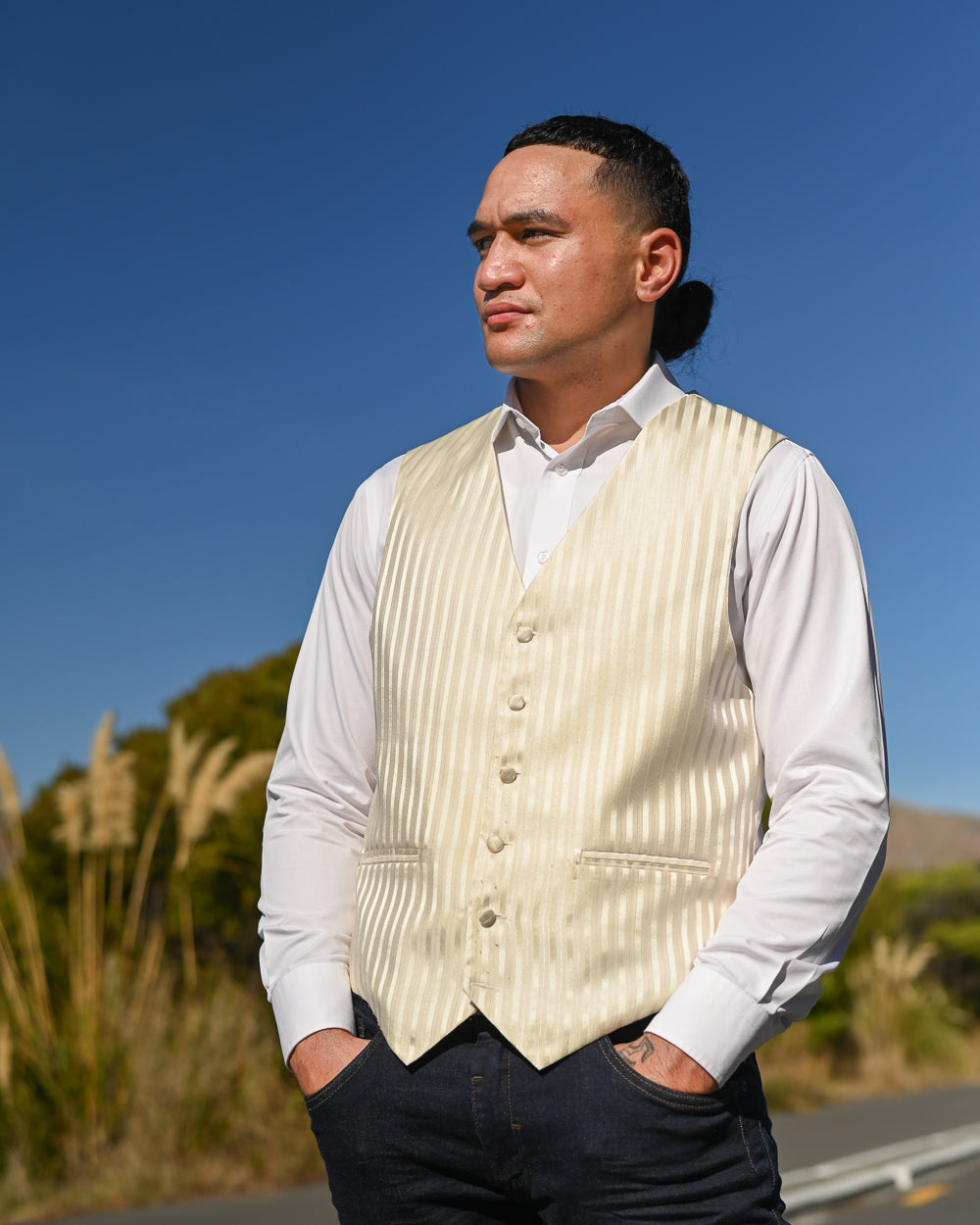 Young man wearing a creamy gold stripe waistcoat with a while shirt and jeans