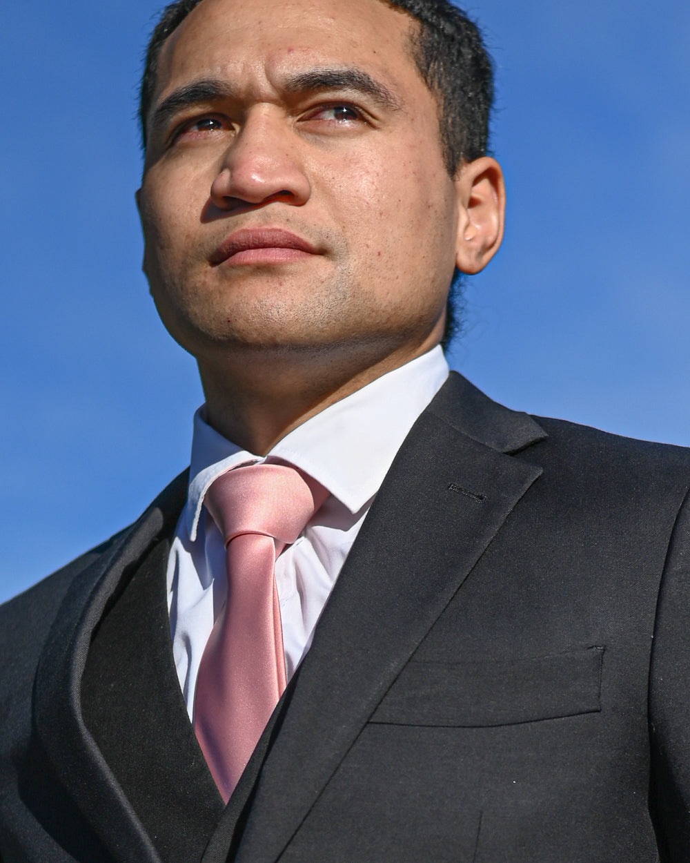 Dark pink silk-look tie worn with a black three-piece suit