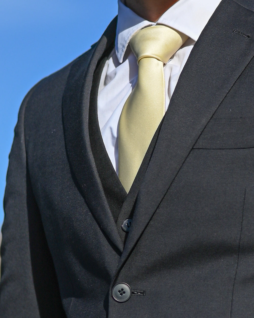 Gold silk-look tie worn with three-piece black suit