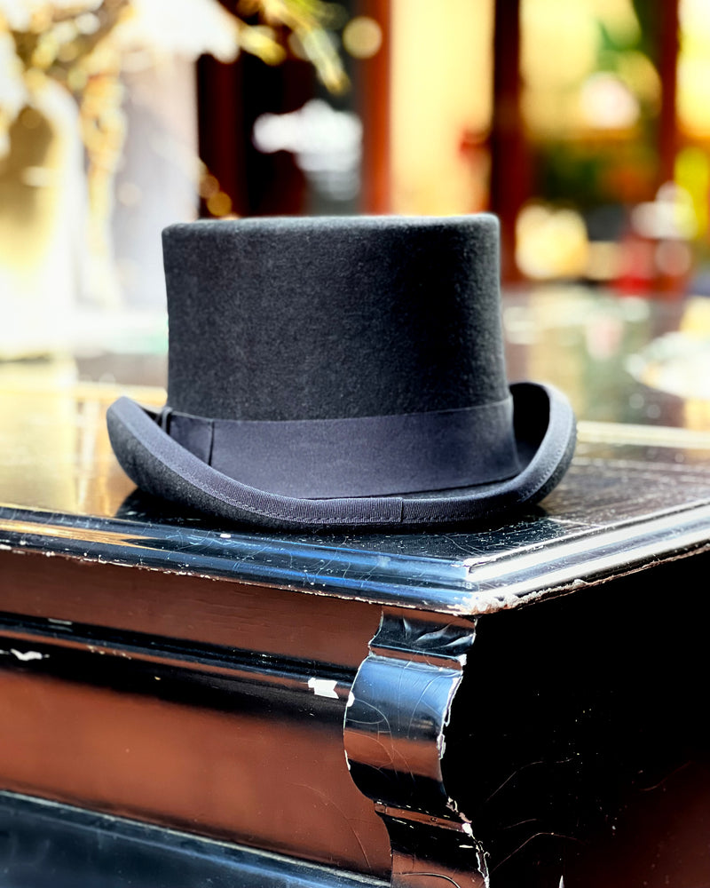 A top hat for hire photographed sitting on a piano