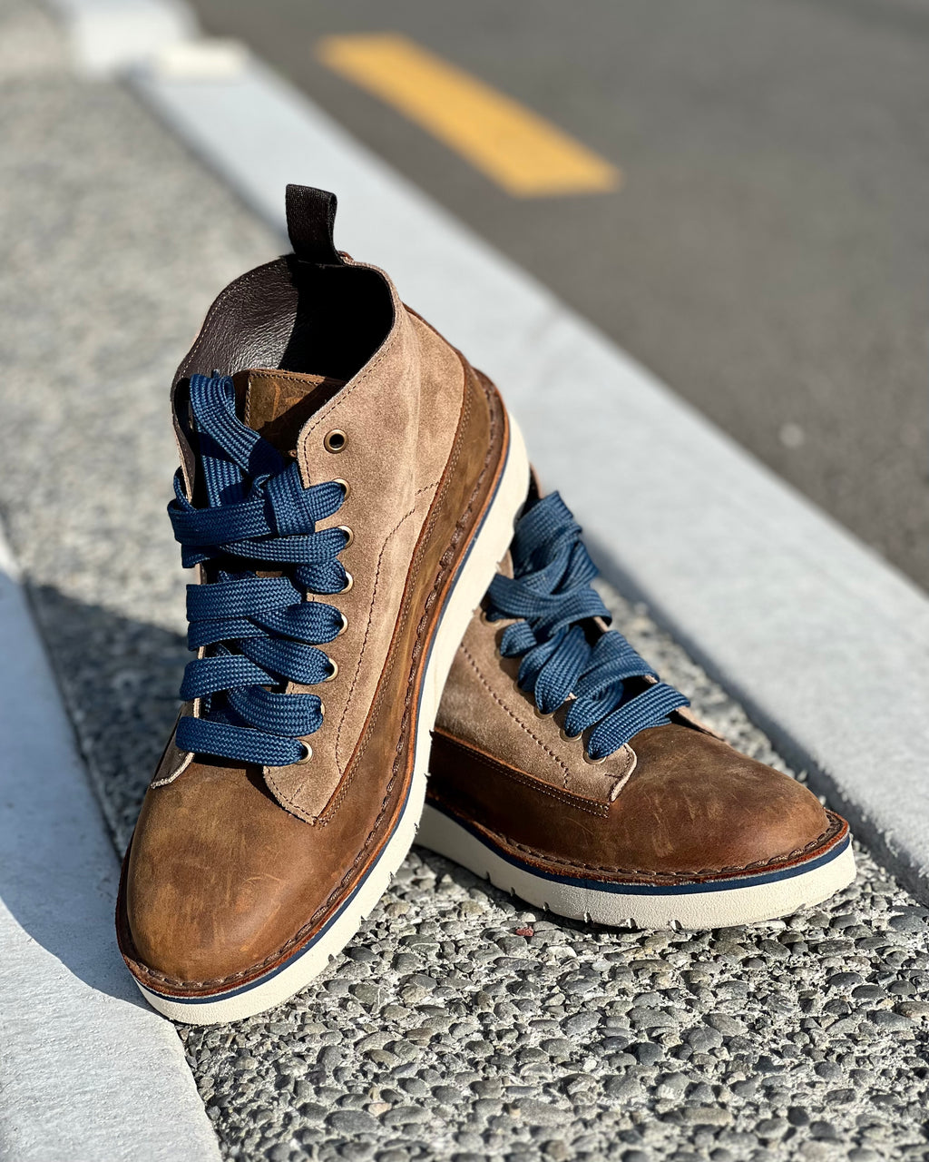 Two-tone suede mens boots by Italiano sitting on a aggregate curb