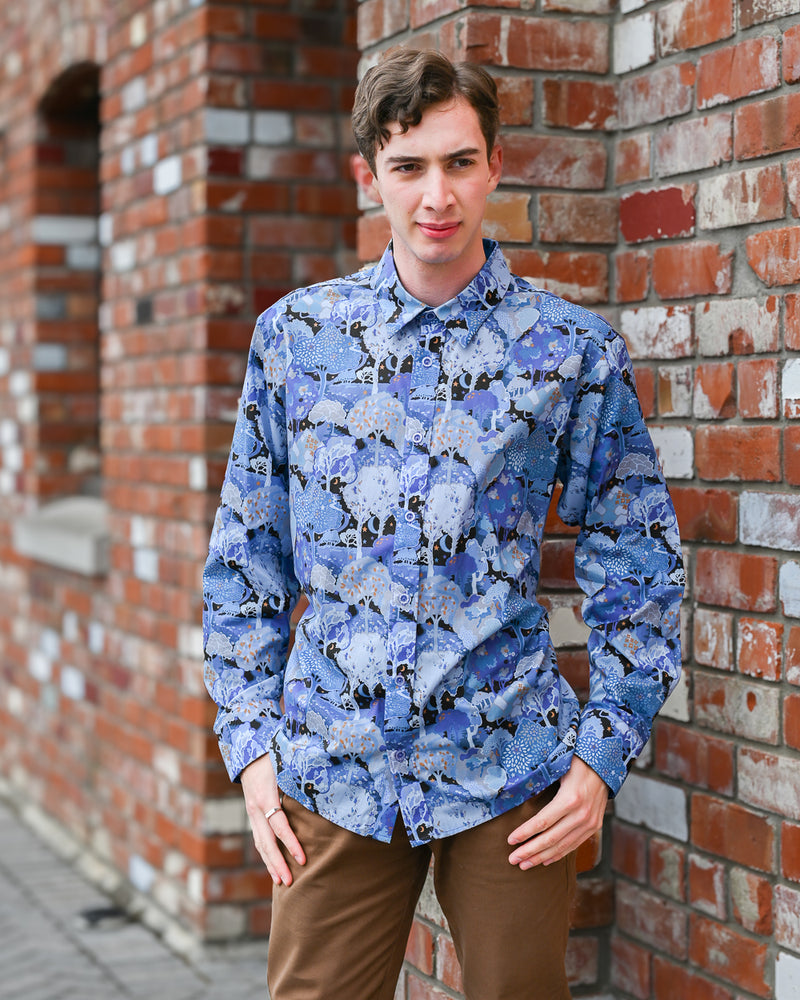 Man wearing a long-sleeve cotton shirt with a blue forest print on it. By Mr Peacock made in NZ