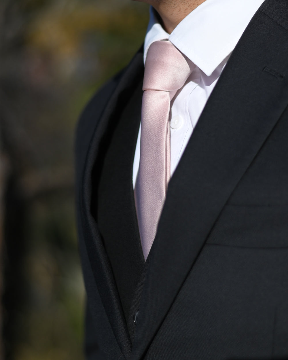 Pale pink silk-look tie worn with a black three-piece suit