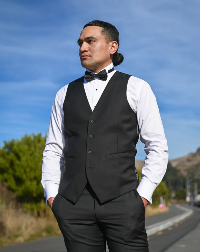 Handsome young man in black waistcoat, white shirt and black bow tie