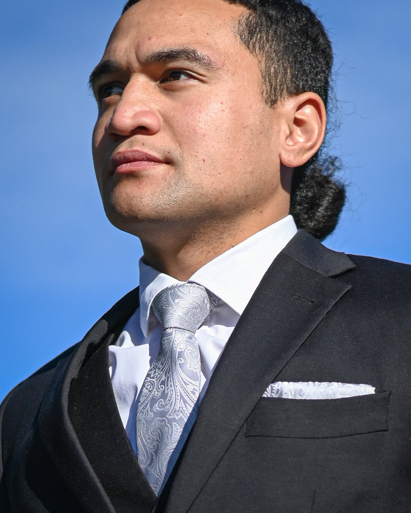 Silver paisley tie worn with matching pocket square and a black suit