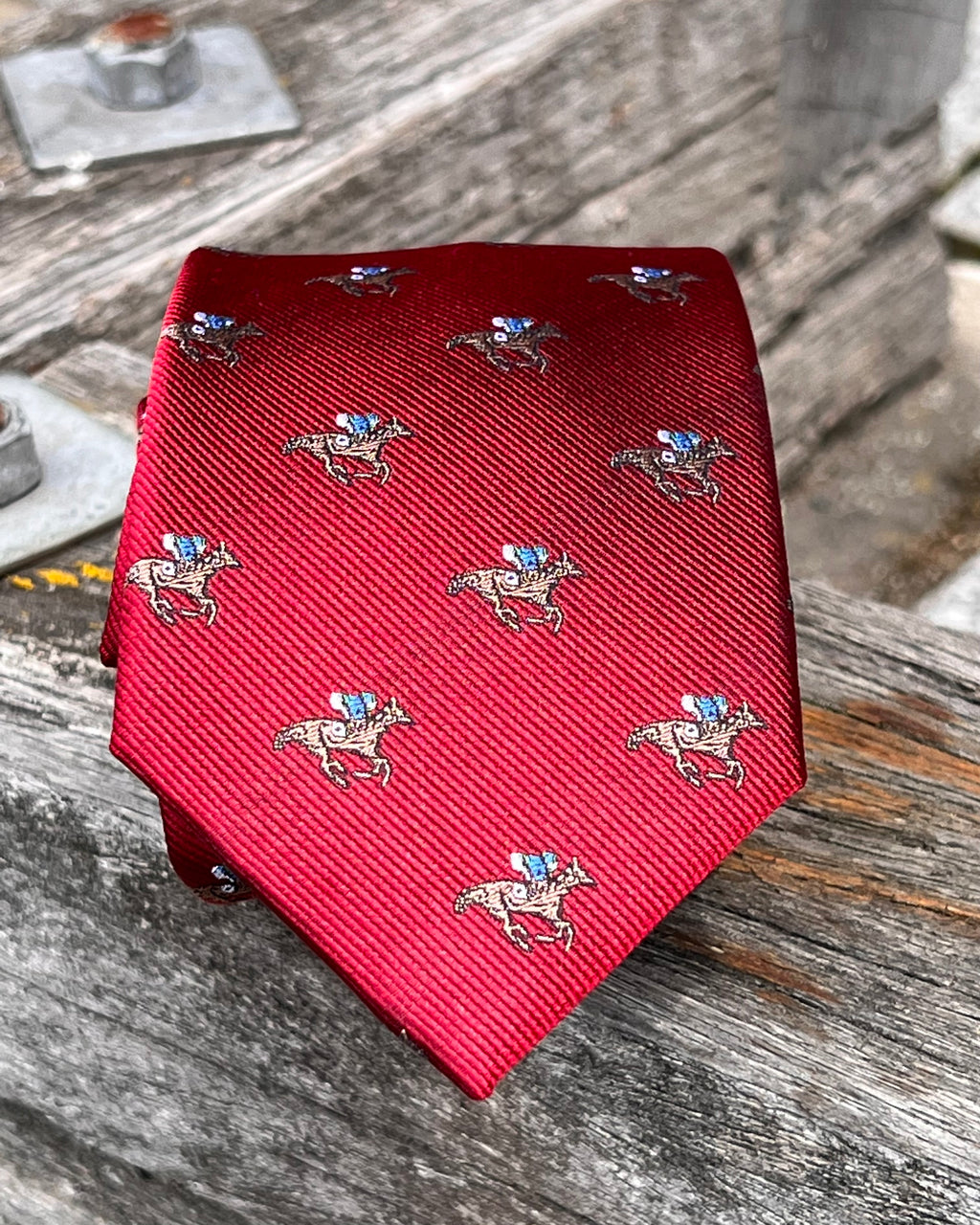 Pure silk tie featuring racehorse motif on dark red background